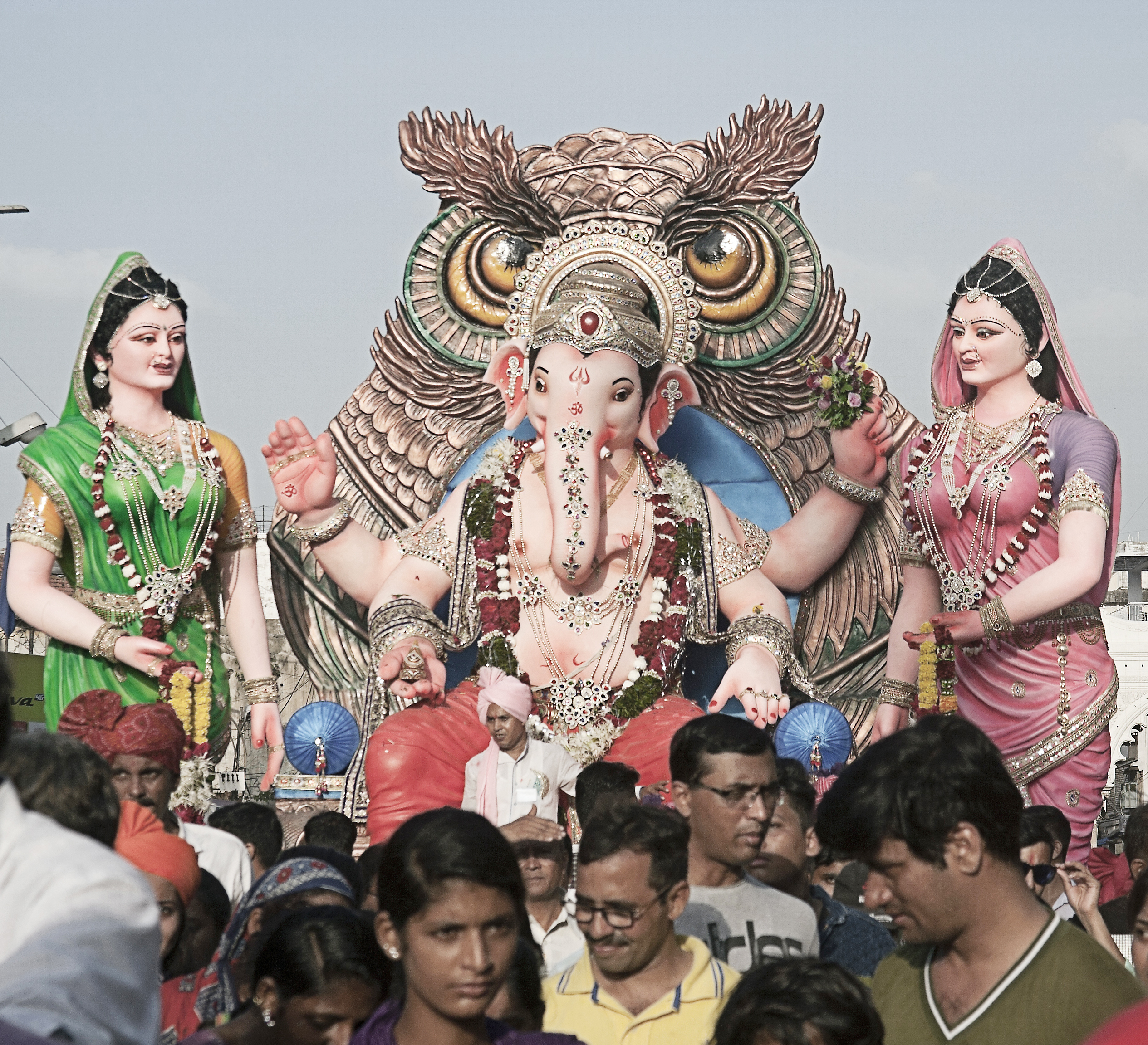 A large Ganesh murthi with two forms of the Divine Mother on either side is carried in a Ganesh Chaturthi Parade
